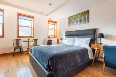 a bedroom with a large bed with a desk and chairs at Onix Studio in Long Island City