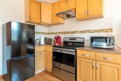 a kitchen with wooden cabinets and a black refrigerator at Onix Studio in Long Island City