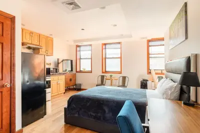 a bedroom with a bed and a kitchen with a refrigerator at Onix Studio in Long Island City