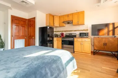 a kitchen with wooden cabinets and a bed in a room at Onix Studio in Long Island City