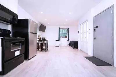 a kitchen with a refrigerator and a living room at Bocca Studio in Long Island City
