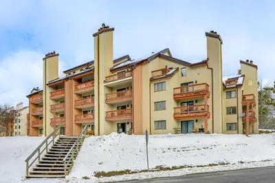 a large apartment building with snow in front of it at Walk to Mount Snow Resort Unit with Pool and Hot Tubs in Dover