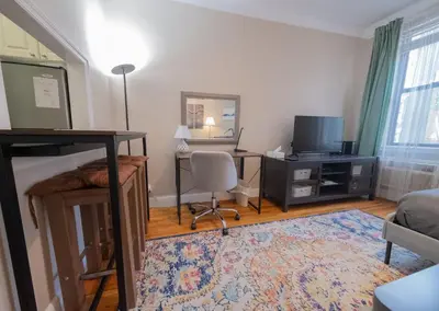 a bedroom with a bunk bed with a desk and a television at Bright Studio in Central NYC in New York