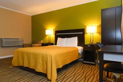 a hotel room with a bed with two lamps and a desk at Capital Inn and Suites in Rensselaer