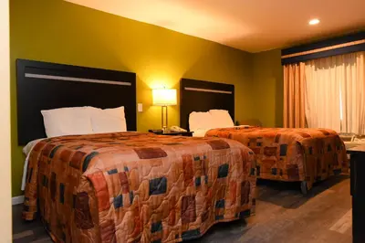 two beds in a hotel room with green walls at Capital Inn and Suites in Rensselaer