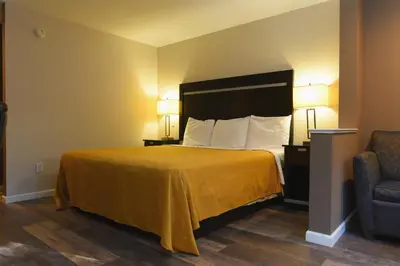a hotel room with a bed and a chair at Capital Inn and Suites in Rensselaer