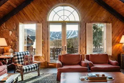 a living room with couches and a large window at Black Bear Cabin in Windham