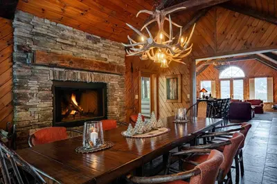 a dining room with a long table and a fireplace at Black Bear Cabin in Windham