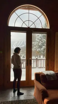 a woman standing in front of a large window at Black Bear Cabin in Windham