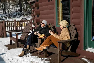 two people sitting on benches in the snow at Black Bear Cabin in Windham