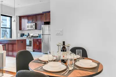 a dining room table with chairs and a kitchen at 20 MIN to Manhattan! 2BR Luxurious Comfy & Spotless in Newark
