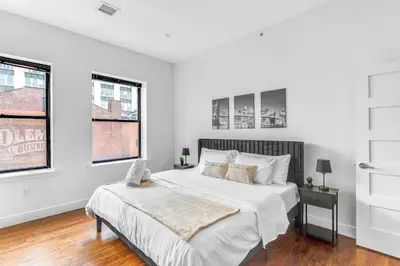 a white bedroom with a bed and two windows at 20 MIN to Manhattan! 2BR Luxurious Comfy & Spotless in Newark