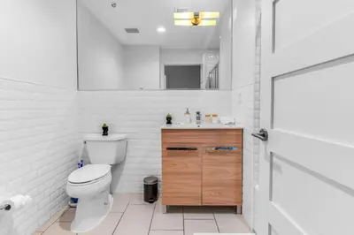 a white bathroom with a toilet and a sink at 20 MIN to Manhattan! 2BR Luxurious Comfy & Spotless in Newark