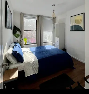 a bedroom with a blue bed and two windows at Chelsea Gem Modern 2BR Apt Prime 23rd & 7th Spot in New York