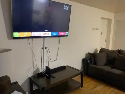 a flat screen tv hanging on a wall in a living room at One Bedroom by Month Next to Bronx Zoo in West Farms