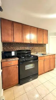 a kitchen with a black stove and wooden cabinets at Friendly Home Near NYC in Little Ferry
