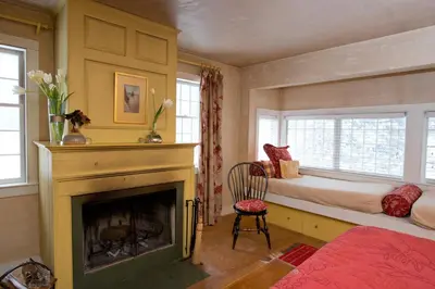 a bedroom with a fireplace and a bed and a window at The Old Inn On The Green in New Marlborough
