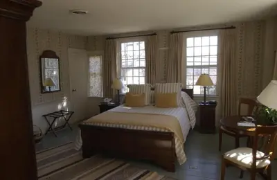 a bedroom with a large bed and two windows at The Old Inn On The Green in New Marlborough
