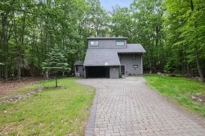 a house in the middle of a brick driveway at Luxurious Poconos Retreat - Hot Tub, Sauna, Games in East Stroudsburg