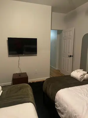a hotel room with two beds and a flat screen tv at 3br 3bath Duplex NY 23 mins in Hoboken