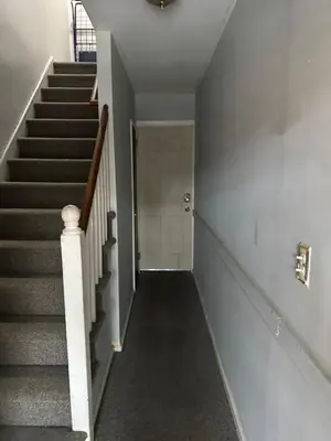 a hallway with stairs and a white door at Your Home away from Home ! UNIT 2- 1st floor in Baychester