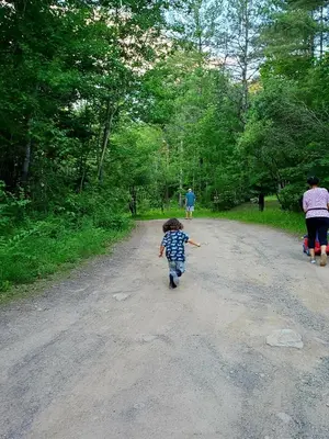 a young child walking down a dirt road at Modern Pine Tree Chalet with HOT TUB, Outdoor TV, VIEWS, Games & POOL 5 mins away!! in Gilboa