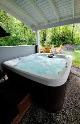 a jacuzzi tub sitting on a patio at Modern Pine Tree Chalet with HOT TUB, Outdoor TV, VIEWS, Games & POOL 5 mins away!! in Gilboa
