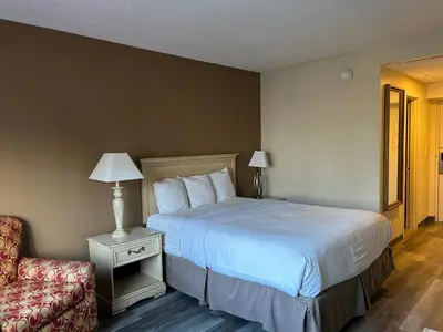 a hotel room with a bed and a chair at Hilltop Inn & Suites in Yonkers