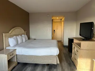 a hotel room with a bed and a flat screen tv at Hilltop Inn & Suites in Yonkers