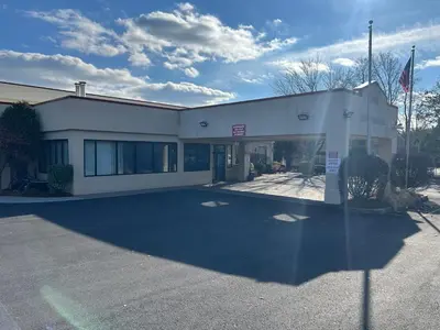 a building with a parking lot in front of it at Hilltop Inn & Suites in Yonkers