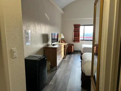 a bedroom with a bed and a dresser and a desk at Hilltop Inn & Suites in Yonkers
