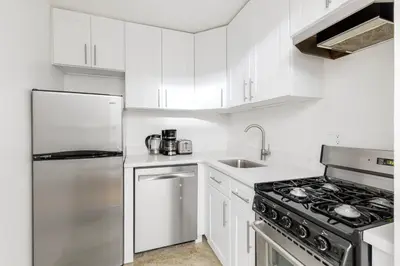 a kitchen with white cabinets and a stainless steel refrigerator at Midtown East 1br w elevator nr transport NYC-1249 in New York
