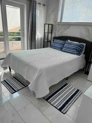 a bedroom with a large bed with white sheets and blue pillows at Skyline Penthouse in Woodside