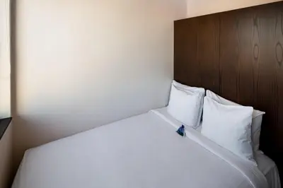 a white bed with a wooden headboard and white pillows at Orchard Street Hotel in New York