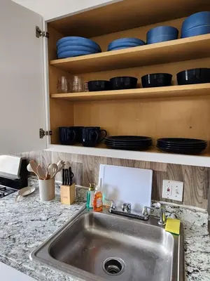 a kitchen counter with a sink and plates on shelves at Elegant Retreat Where Relaxation Embraces Design in Springfield
