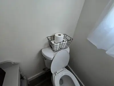 a bathroom with a toilet with a basket of toilet paper at The Jefferson Guest House in Litchfield