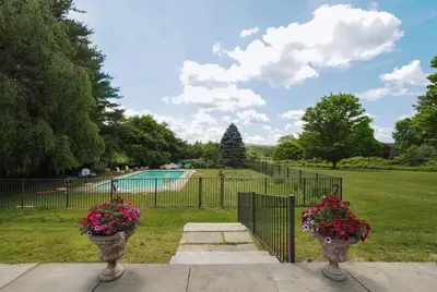 a fence with two flowers inront of a pool at Charming 6 Bdrm Countryside Stay, Sauna and HotTub in North Egremont