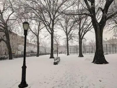 a snow covered park with a bench and a light pole at Cozy Brooklyn Home, Private Room in Host Shared Apartment in Brooklyn