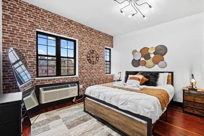 a brick walled bedroom with a bed and a window at Rustic Chic 4BR for Groups - Bushwick's Finest Stay in Brooklyn