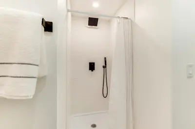 a white bathroom with a shower with a shower curtain at Centrally Located and Pet Friendly Yonkers Studio! in Yonkers