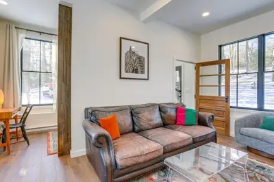 a living room with a leather couch and a table at Waterfront Studio with Loft and Dock Near Narrowsburg! in Narrowsburg