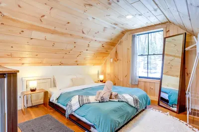 a woman laying on a bed in a room at Waterfront Studio with Loft and Dock Near Narrowsburg! in Narrowsburg