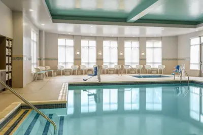 a pool in a room with chairs and tables at Hilton Garden Inn Lenox Pittsfield in Pittsfield