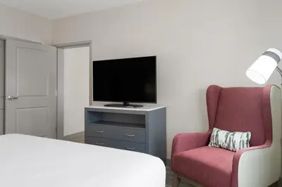 a bedroom with a bed and a tv and a chair at Hilton Garden Inn Lenox Pittsfield in Pittsfield