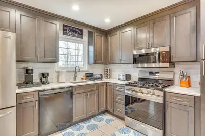 a kitchen with wooden cabinets and stainless steel appliances at 4 Mi to Hudson River Cozy Newburgh Home! in Newburgh