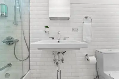 a white bathroom with a sink and a shower at SWJ544FH Huge 6BR 4BA Backyard Access in New York