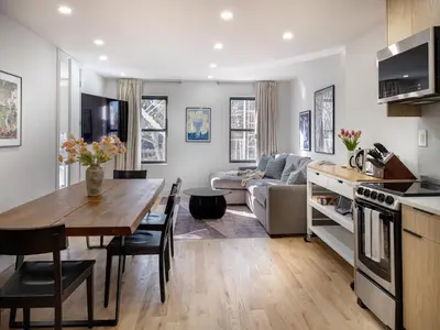 a kitchen and living room with a table and a couch at Three-Bedroom Suite in Prime Williamsburg in Brooklyn