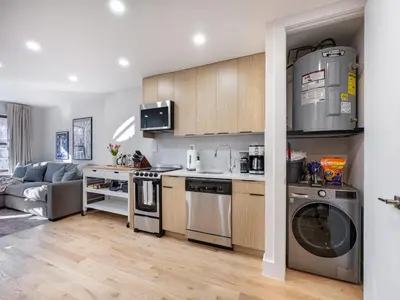a kitchen with stainless steel appliances and a living room at Three-Bedroom Suite in Prime Williamsburg in Brooklyn