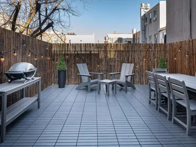 a patio with chairs and tables and a fence at Three-Bedroom Suite in Prime Williamsburg in Brooklyn