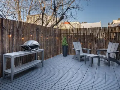 a patio with benches and a grill and a fence at Three-Bedroom Suite in Prime Williamsburg in Brooklyn